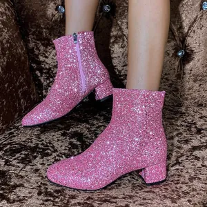 Close-up of sparkly pink sequin ankle boots with chunky heels and zipper detail.