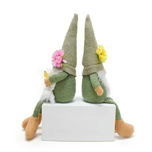 Side view of two spring faceless gnomes with floral hats sitting on a white pedestal box.