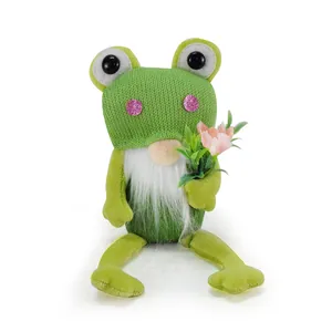 Close-up detail of a charming green frog gnome plush doll holding a delicate pink flower