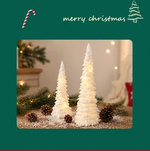Close-up of white resin LED mini Christmas trees with warm light and snow texture