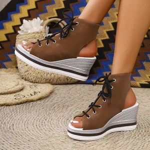 Close-up of brown lace-up open-toe wedge sandals with silver woven platform sole.