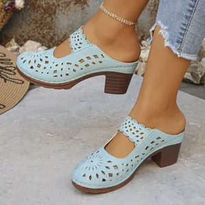 Detailed macro view of light blue laser-cut chunky heel mules with floral hollow patterns