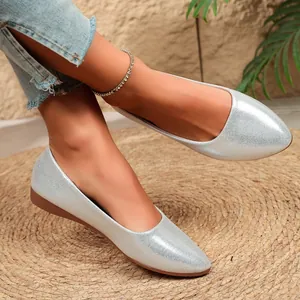 Detailed close-up of silver glittery pointed-toe flat shoes worn on model feet
