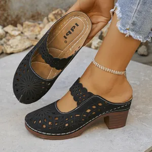Detailed view of women's black hollow-out heeled clogs with floral laser-cut patterns.
