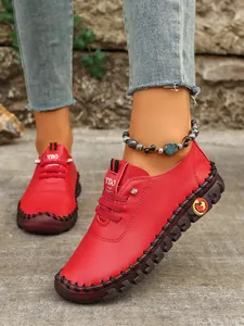 Vista detallada de los zapatos informales rojos cosidos a mano para mujer en los pies de modelo