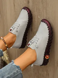 Vista de detalle de mocasines grises para mujer con suelas gruesas marrón rojizo cosidas