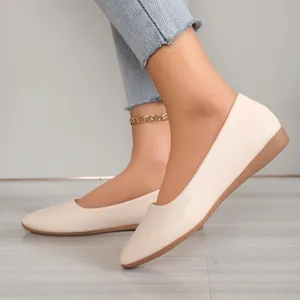 Detailed side view of elegant beige pointed-toe flat shoes worn with denim jeans