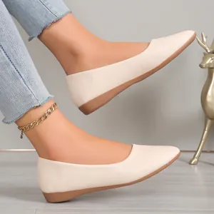 Detailed view of fashionable cream pointed-toe ballet flats worn with a stylish gold anklet.
