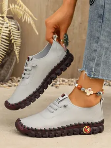 Detalle de zapatos casuales grises cosidos a mano para mujer con suelas planas gruesas