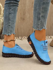 Primer plano de mocasines azules cosidos a mano para mujer con suela de goma texturizada.