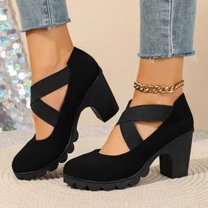Close-up of stylish black platform high heels featuring cross elastic straps and thick heels.