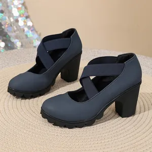Detail of navy blue thick-heeled pumps with cross elastic straps and platform soles.
