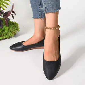 Stylish black pointed-toe flat shoes with a decorative gold chain anklet detail.