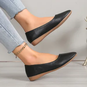 Close-up of black pointed-toe flat shoes with textured leather and light brown soles.