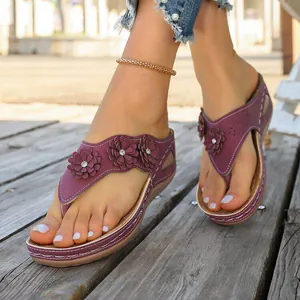 Chanclas de cuña moradas para mujer con adornos florales y detalles calados.