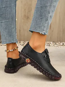 Vista lateral detallada de los zapatos planos de cuero negro cosidos a mano para mujer