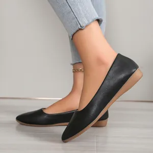 Side view detail of black pointed toe flat shoes with non-slip wedge sole.