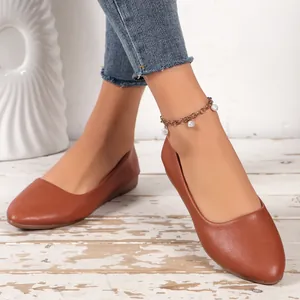 Detailed close-up of brown faux leather pointed-toe flats worn with a pearl anklet