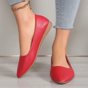 Close-up of elegant red pointed-toe flats with litchi grain texture on a model's feet.