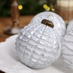 Vintage silver Christmas ball ornament with grid texture and glitter on a white plate