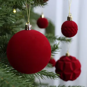 Red flocked Christmas ball ornaments set hanging on a green festive tree