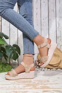 Detailed view of beige wedge sandals with buckle straps and woven platform sole