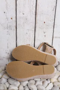 Close-up view showing the anti-slip wavy rubber outsole of beige wedge sandals