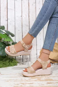 Detailed view of beige wedge platform sandals with buckle straps worn with jeans