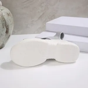 Close-up van de getextureerde antislip witte plateauzool van een grijze geweven sandaal.