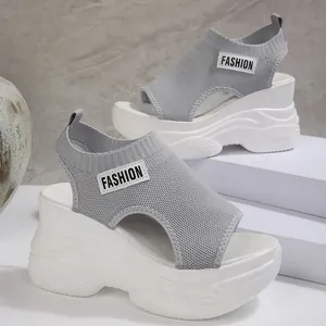 Detailopname van grijze gebreide platformsandalen met witte sleehak en patch.