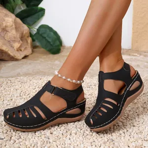 Close-up detail of black wedge sandals with white stitched platform and closed toe design