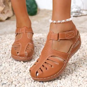 Close-up of brown women's wedge sandals with white contrast stitching and cut-outs