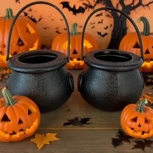 Close-up of two black Halloween candy cauldrons with pumpkin lanterns background