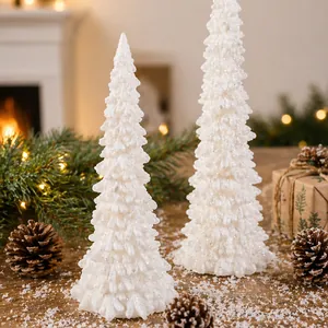 Pair of elegant white resin LED Christmas tree night lights on a snowy wooden tabletop