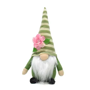 Detailed view of plush spring gnome with green striped hat and pink peach blossom