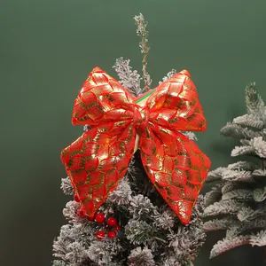 Detailed macro view of a red and gold woven Christmas bow on a festive tree branch.