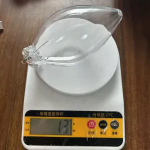 Vista detallada de un adorno navideño de PET transparente que pesa 13 g en una báscula precisa