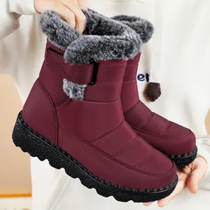 Detailed view of burgundy waterproof snow boots with plush fur trim and velcro strap.