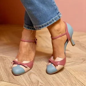 Nahaufnahme stilvoller Stöckelschuhe mit Farblock-Design, Schleife und Knöchelriemen