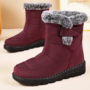 Detail view of wine red women snow boots with grey faux fur trim and textured sole.