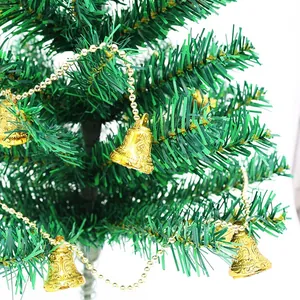 Primer plano de campanas doradas en relieve con cadena de cuentas en un árbol de Navidad