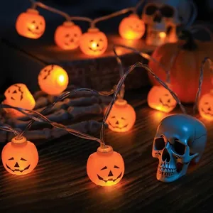 Nahaufnahme von leuchtenden Halloween Kürbis-Lichterketten auf dunklem Holzgrund