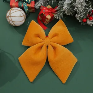 Close-up detail of a large yellow velvet Christmas bow on a festive green background