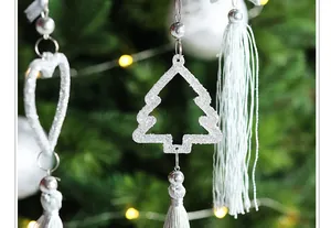 Detailopname van witte glinsterende kerstboom en hartornamenten met kwastjes