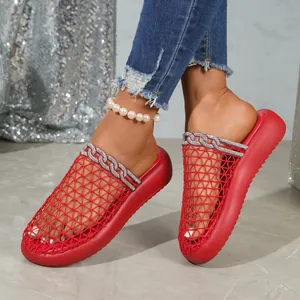 Close-up of red mesh mule slippers with rhinestone chain detail and pearl anklet