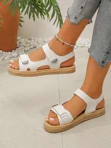 Dettaglio di sandali bianchi con zeppa, cinturini in velcro e suola effetto corda