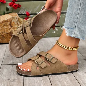 Nahaufnahme von stilvollen braunen Wildledersandalen mit doppelten Gold-Schnallen und Korksohle