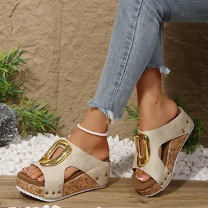 Detailed view of women's beige wedge sandals featuring a large gold buckle and cork platform