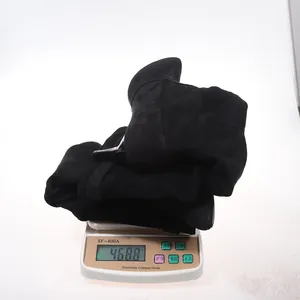 Close-up of black suede pointed-toe stiletto boots on a scale, weighing 468.8g.