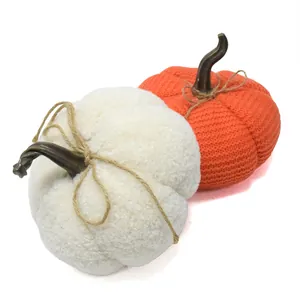 Nahaufnahme von dekorativen gestrickten orangefarbenen und weißen Sherpa-Stoffkürbissen
